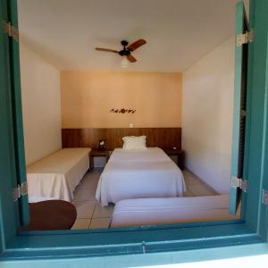 a bedroom with two beds and a ceiling fan at Pousada Vila Cocais in Cocais +20 photos
