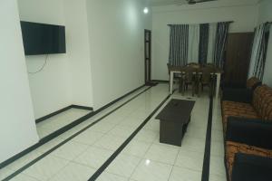 a living room with a couch and a tv on a wall at T-Nova Guest House in Trincomalee
