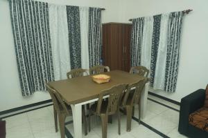 a dining room with a table and chairs and curtains at T-Nova Guest House in Trincomalee