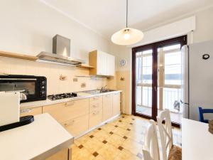 a kitchen with white cabinets and a large window at Appartamento Miramare in Follonica