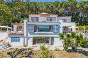 a large white house with blue accents at Locus Solus Elba in Casa Marchetti