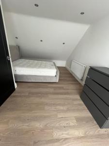 a bedroom with a bed and a wooden floor at Deluxe family room in Chessington