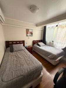 a bedroom with two beds and a window at Hostal Matta in Antofagasta