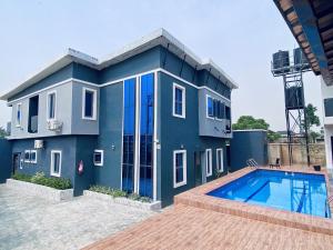 a blue house with a swimming pool in front of it at Wesmont Hotels in Ikorodu