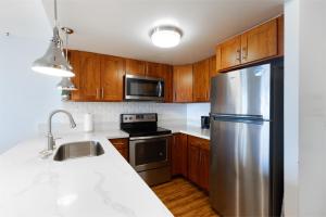 a kitchen with wooden cabinets and a stainless steel refrigerator at Ilikai Marina 1394 in Honolulu