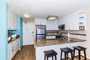 a kitchen with white cabinets and black stools at Ilikai Marina 984 in Honolulu +13 photos