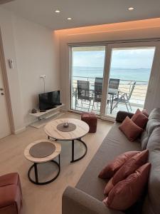 a living room with a couch and tables and a view of the ocean at Sea View Luxury Apartment Beachfront 3BR in Agia Triada