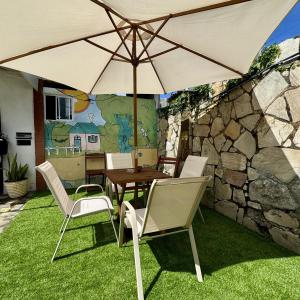 a table and chairs with an umbrella on the grass at Pousada SolMaris in João Pessoa