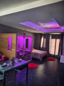 a room with a bed and a table and purple lights at Suite Romantica con Jacuzzi e Sauna in Porto Empedocle