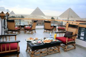 a balcony with a table and chairs with pyramids in the background at Egypt Aziz pyramids in Cairo +29 photos