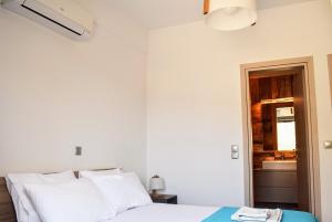 a bedroom with a bed with white pillows and a window at Delta Villa's Kythnos II in Kithnos