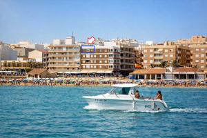 two people on a boat in the water near a beach at Emilia's Cabin in Guardamar del Segura