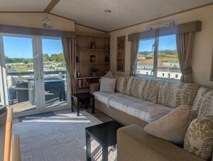 a living room with a couch and large windows at Three lochs holiday park Loch view 123 in Balminnoch