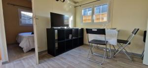 a room with a table and two chairs and a television at Bungalow entre oliviers et pins, -10mn de la plage in Châteauneuf-lès-Martigues