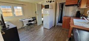 a small kitchen with a refrigerator and a sink at Bungalow entre oliviers et pins, -10mn de la plage in Châteauneuf-lès-Martigues