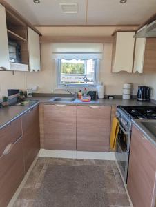 a kitchen with a sink and a stove top oven at Three lochs holiday park Loch view 123 in Balminnoch
