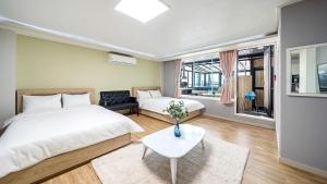 a bedroom with two beds and a couch and a table at Geoje Memory Kidspoolvilla in Geoje