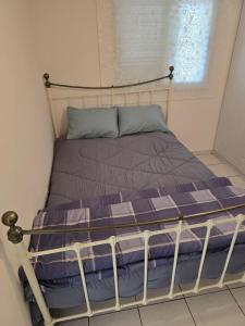 a bed with a purple comforter and a window at Indie little house in Limassol