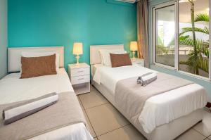 a bedroom with two beds and a blue wall at Plage Bleue D2 in Trou aux Biches +13 photos