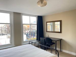 a bedroom with a bed and a desk and windows at Bedroom Dordrecht Centrum - La Focaccina in Dordrecht