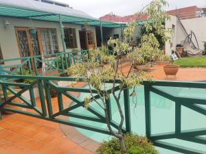 a house with a green railing and a tree at Valleycenter guestlodge in Johannesburg