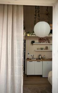 a kitchen with white cabinets and a white lamp at Airport Moonlight Tallinn in Tallinn