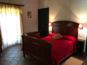 a bedroom with a wooden bed with a red blanket at Cortijo Viña del Duco in Azuaga