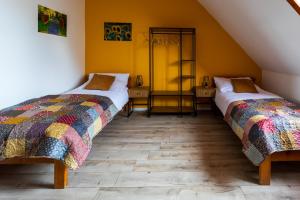 two beds in a room with yellow walls at Mitter-ház Panzió in Zalaszentgrót