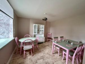 a dining room with pink chairs and a table at An Teach Ban in Tralee