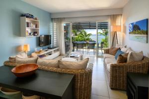 a living room with a couch and chairs and a television at Plage Bleue D2 in Trou aux Biches