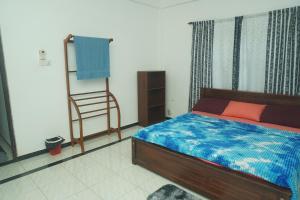 a bedroom with a bed and a chair in it at T-Nova Guest House in Trincomalee