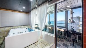 a large bathroom with a tub with a view of the ocean at Geoje Memory Kidspoolvilla in Geoje
