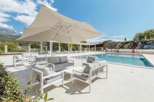 a group of chairs and an umbrella next to a pool at Apartments with Pool 5 Min Walk to Beach in Igalo