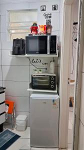 a kitchen with a microwave and a refrigerator at Minicasa Show! in Jandira