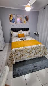 a bedroom with a large bed with a yellow blanket at Minicasa Show! in Jandira