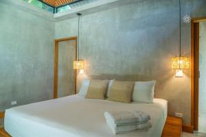 a bedroom with a large white bed with two lights at Serenity Bungalow in Cocles