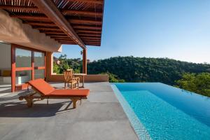 a house with a pool and a chair next to it at Villa La Ceiba in La Huerta