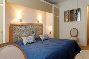 a bedroom with a blue bed with two pillows at Domaine d'Auriac - Relais & Châteaux in Carcassonne