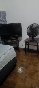 a bedroom with a television and a chair on a table at pousada popular in Barreiras +3 photos