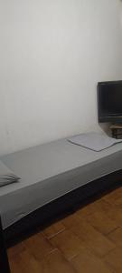 a bed in a room with a white wall at pousada popular in Barreiras