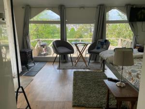 a living room with a table and chairs and windows at Honey Bee Cabin in Llandysul