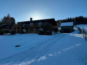 a log cabin in the snow with a driveway at Le Caroline du Nord in Tenneville