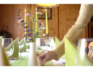 
a woman is cutting a vase with flowers in it at Landgasthof Sengstbratl in Wallsee
