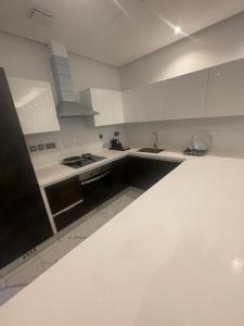 a white kitchen with white cabinets and a sink at Al Safwa One in Al Ḩadd
