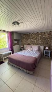 a bedroom with a bed and a stone wall at Le Mas de la Colombe in Grospierres