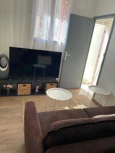 a living room with a couch and two tables and a large tv at Villejuif IGR in Villejuif