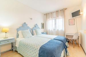 a bedroom with a blue and white bed and a window at Host In Olivença in Vila Nova de Famalicão