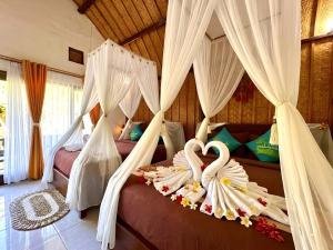 a bedroom with two beds with white drapes at Meket Bungalows in Nusa Penida +50 photos