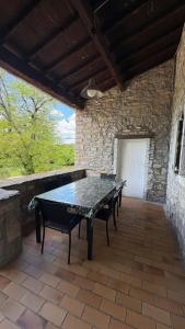 a table and chairs on a patio with a stone wall at Le Mas de la Colombe in Grospierres