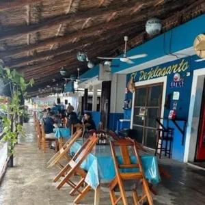 a restaurant with wooden chairs and people sitting outside of it at Posada El Pejelagarto in Bacalar